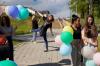Grupa ludzi trzyma balony i spaceruje.