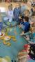 Dzieci siedzą na dywanie i zbierają kolorowe konfetti.