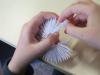 Na zdjęciu fragment dłoni dziecka, który wykonuje pracę origami. 