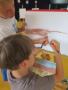 Na zdjęciu dzieci malujące na kartce papieru. 