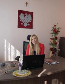 Na zdjęciu widoczna kobieta siedząca za biurkiem