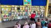 Na zdjęciu grupka dzieci słuchająca, gdy pani bibliotekarka czyta.