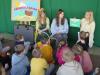 Na zdjęciu Pani Wiosna wraz z młodą dziewczyną i panią czytają książkę przedszkolakom.