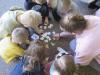 Na zdjęciu grupka dzieci wraz z panią podczas zabawy w układanie puzzli.